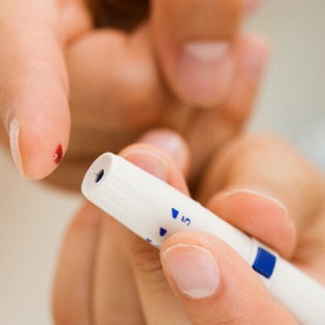 Person using blood sugar monitor on finger --- Image by © Tetra Images/Corbis